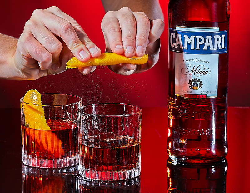 Image of an orange being expressed over a Campari Negroni